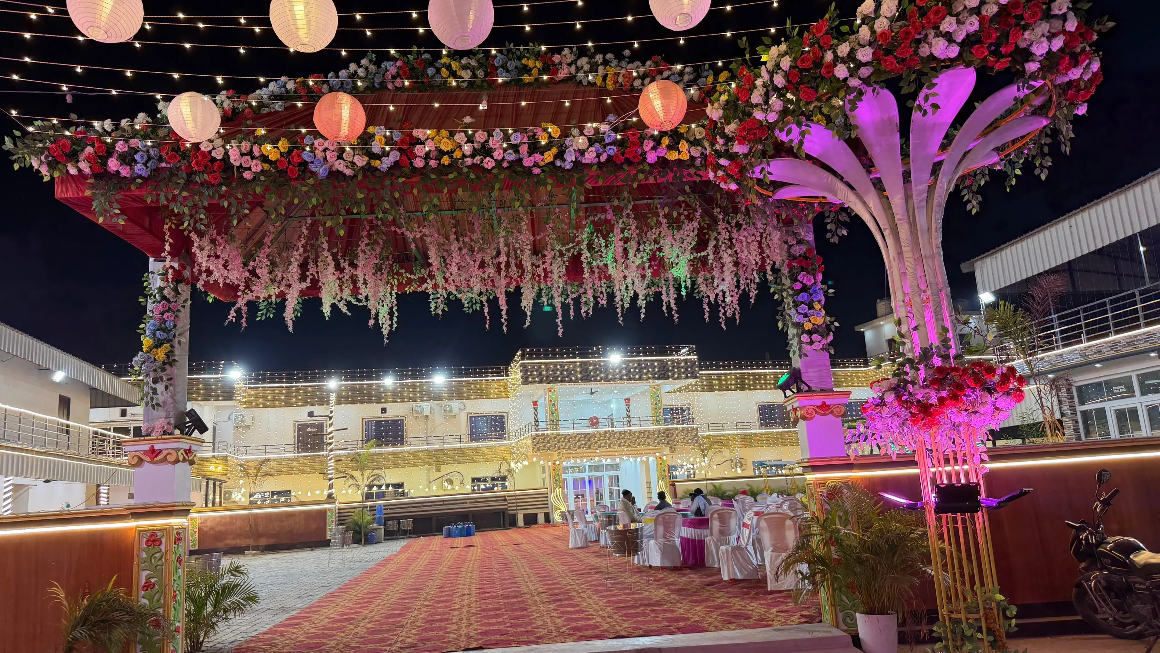 The wedding mandap at Janki Resort at night, under a canopy of flowers and paper lanterns, with the lit building behind
