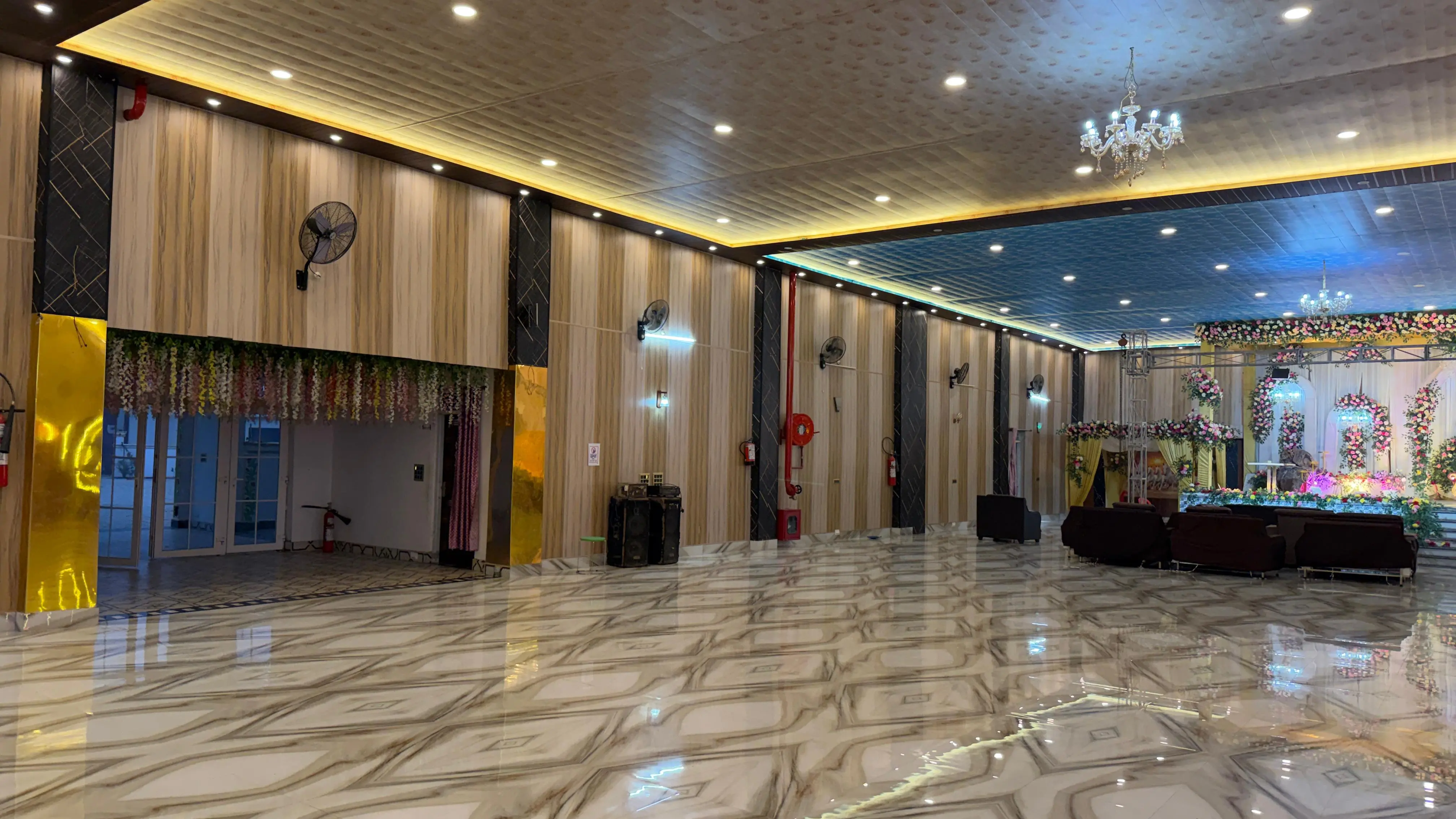 Inside the central hall: polished marble floor, wood-panelled walls, chandeliers and a decorated stage at the far end